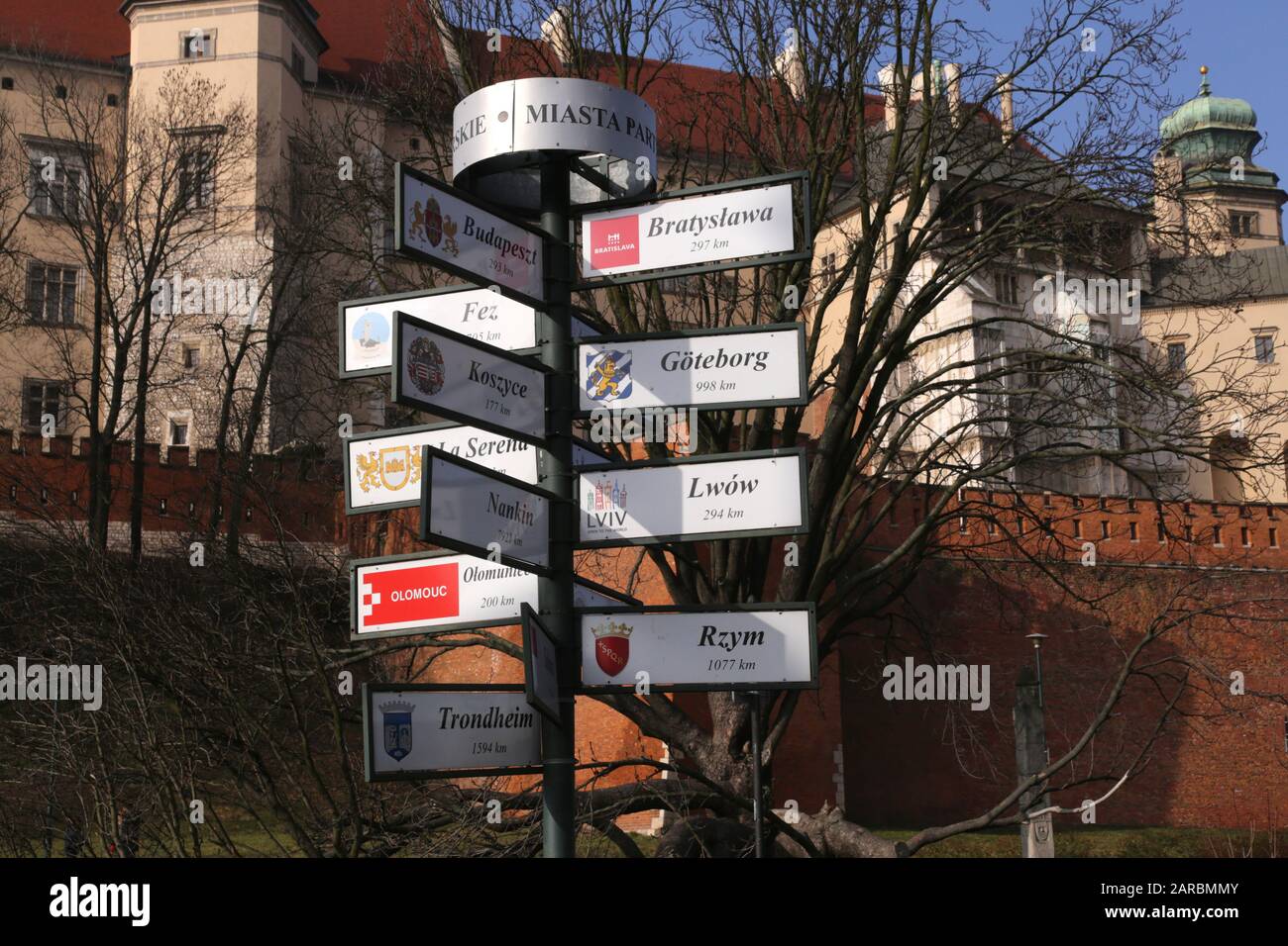 Cracow. Krakow. Poland. Signpost showin direction and distances to Cracow`s twin cities in the center of the Old Town in front of  Wawel castle. Stock Photo